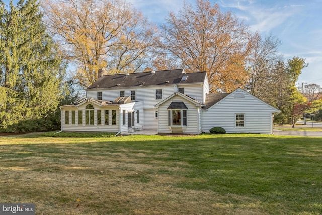 rear view of property featuring a lawn, a patio area, and a sunroom