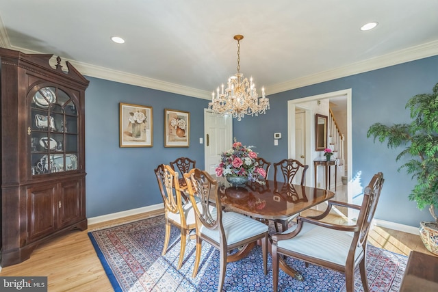 dining area featuring ornamental molding, a notable chandelier, and light wood-type flooring