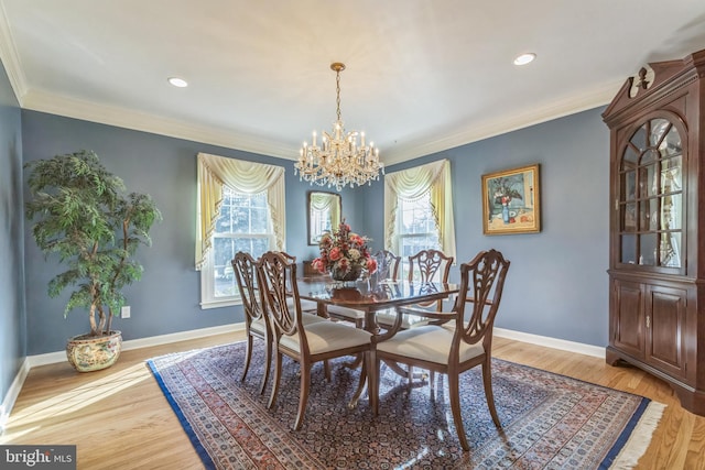 dining space with ornamental molding, wood-type flooring, and an inviting chandelier