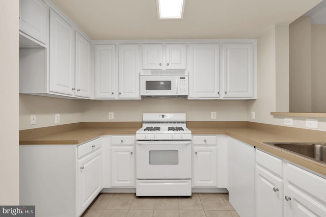 kitchen with white appliances, white cabinetry, and light tile patterned flooring