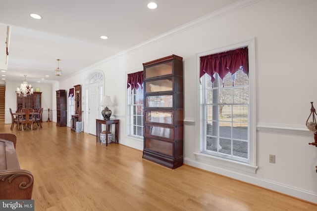 entrance foyer featuring light hardwood / wood-style floors, an inviting chandelier, and ornamental molding