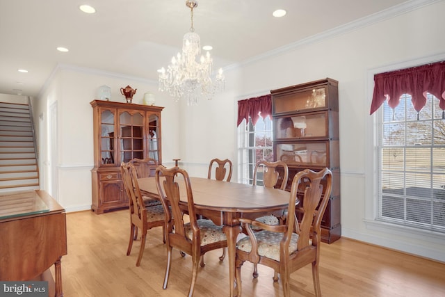 dining area with light hardwood / wood-style floors, crown molding, and an inviting chandelier