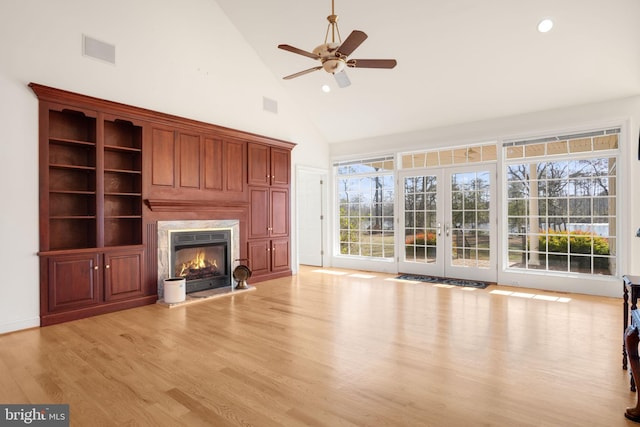 unfurnished living room with ceiling fan, a healthy amount of sunlight, light hardwood / wood-style floors, and high vaulted ceiling