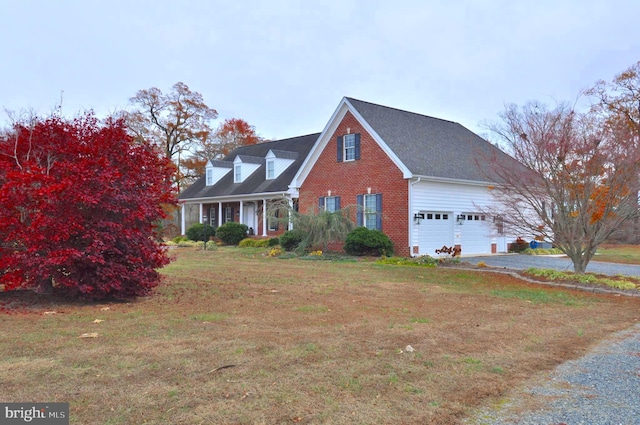 cape cod home featuring a garage and a front lawn