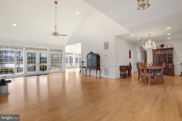 living room with plenty of natural light, light wood-type flooring, ceiling fan with notable chandelier, and high vaulted ceiling