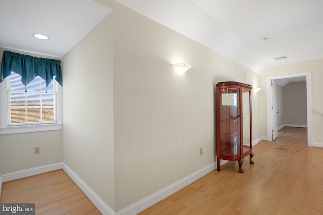 corridor featuring light hardwood / wood-style floors and vaulted ceiling