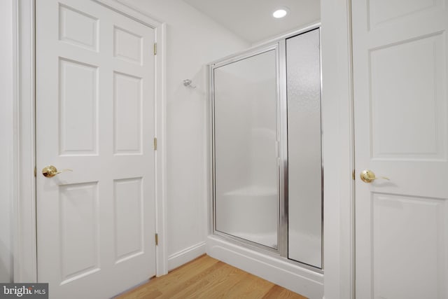 bathroom with hardwood / wood-style floors and a shower with door