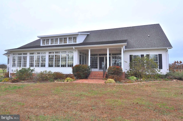 rear view of house featuring a yard and a sunroom