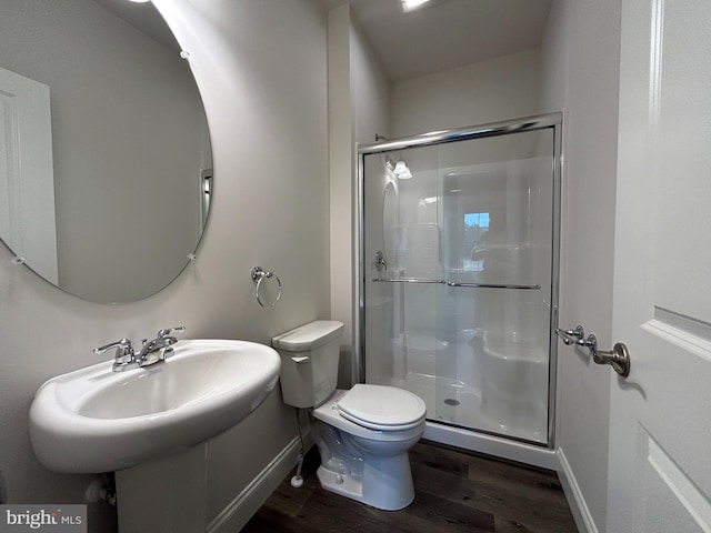 bathroom with hardwood / wood-style flooring, toilet, and a shower with door