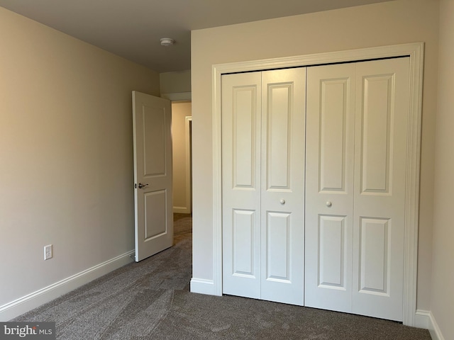 unfurnished bedroom featuring dark carpet and a closet