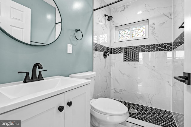 bathroom featuring a tile shower, vanity, and toilet