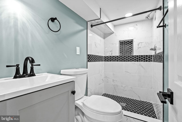 bathroom with tiled shower, vanity, and toilet