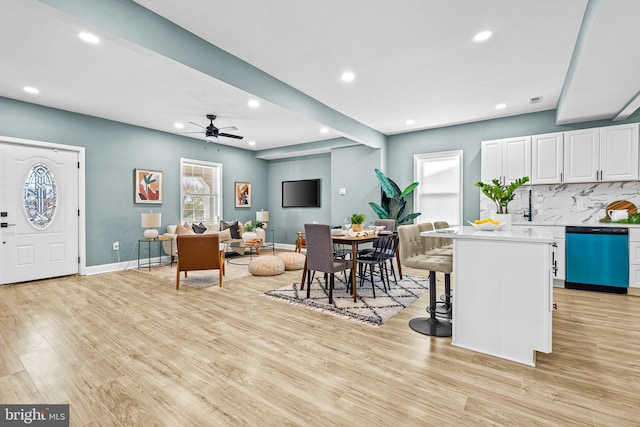 kitchen featuring white cabinets, dishwasher, a healthy amount of sunlight, and a breakfast bar