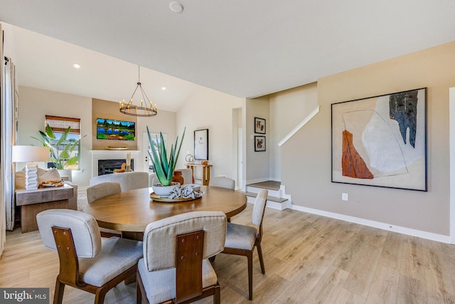 dining space featuring light hardwood / wood-style floors, lofted ceiling, and an inviting chandelier