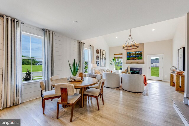 dining room with a wealth of natural light, a chandelier, lofted ceiling, and light wood-type flooring