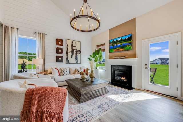 living room featuring light hardwood / wood-style flooring, high vaulted ceiling, and a chandelier