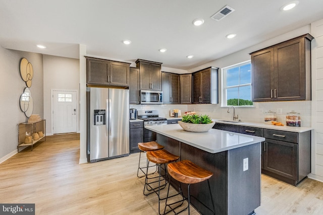 kitchen with light wood-type flooring, a kitchen breakfast bar, a center island, and stainless steel appliances