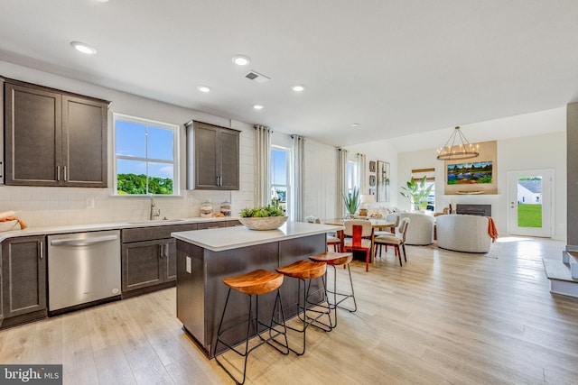 kitchen with dishwasher, a center island, sink, light hardwood / wood-style floors, and a breakfast bar area