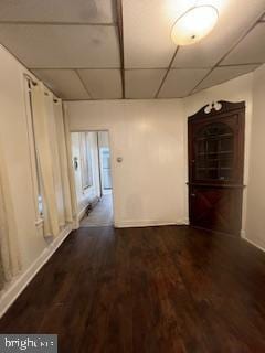 hall with a paneled ceiling and dark hardwood / wood-style flooring