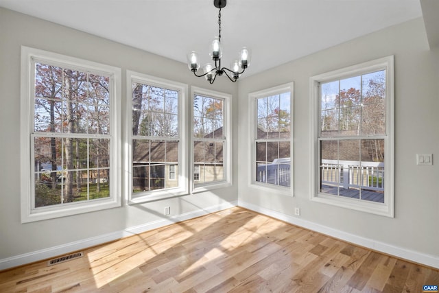 unfurnished dining area featuring light hardwood / wood-style flooring and a chandelier