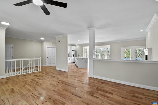 spare room with ceiling fan with notable chandelier, light wood-type flooring, and crown molding