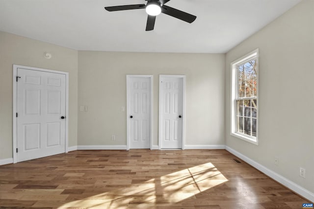 unfurnished bedroom with multiple closets, ceiling fan, and light hardwood / wood-style floors