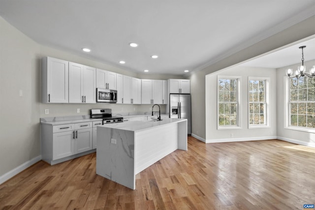 kitchen with white cabinetry, stainless steel appliances, decorative light fixtures, and light hardwood / wood-style floors