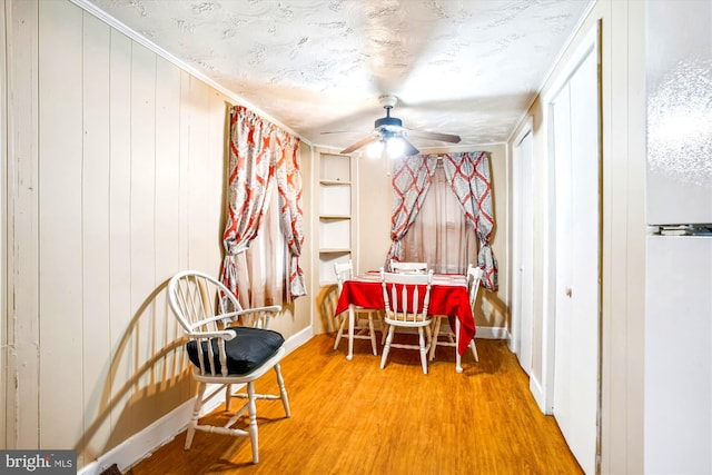 dining room with ceiling fan, hardwood / wood-style floors, and wooden walls