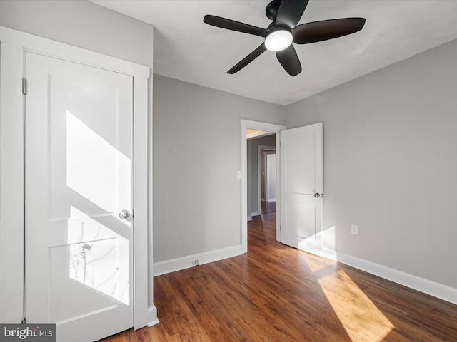 unfurnished bedroom with ceiling fan and dark wood-type flooring