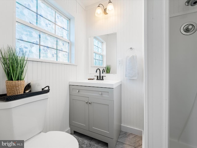 bathroom with a wealth of natural light, an inviting chandelier, vanity, and toilet