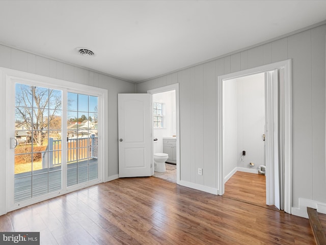 unfurnished bedroom with access to outside, ensuite bathroom, and wood-type flooring