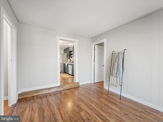 spare room featuring wooden walls, sink, and wood-type flooring