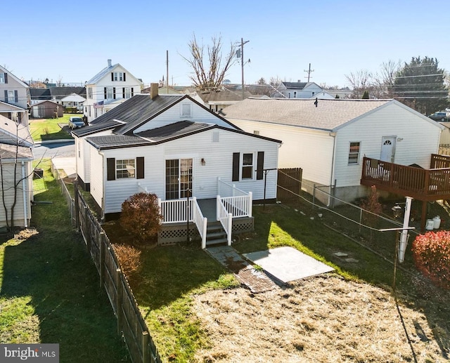 back of property with a wooden deck and a lawn