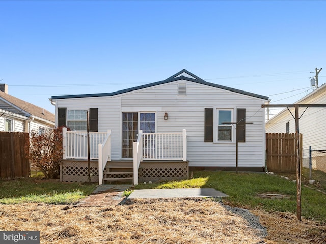 rear view of property featuring a wooden deck and a yard