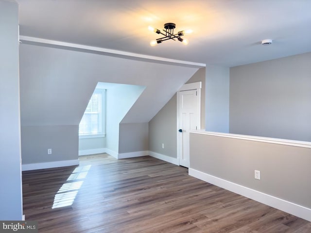 additional living space featuring lofted ceiling, dark hardwood / wood-style floors, and a notable chandelier