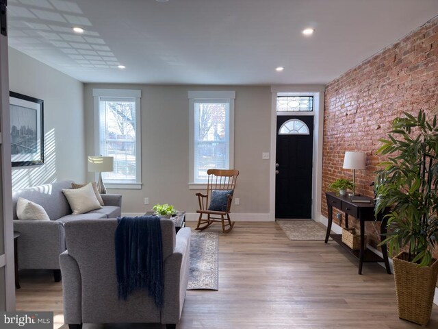 living room featuring brick wall and light wood-type flooring