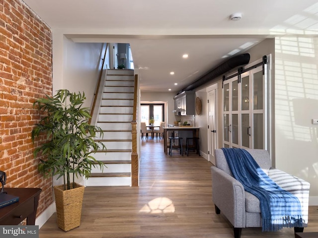 interior space featuring a barn door, wood-type flooring, and brick wall