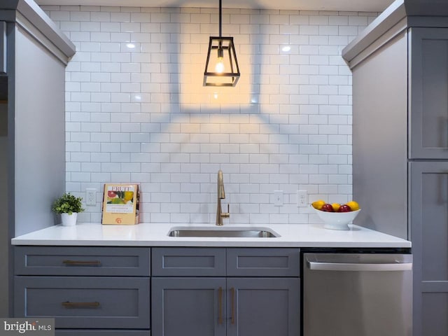 kitchen featuring sink, stainless steel dishwasher, backsplash, pendant lighting, and gray cabinets