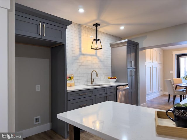 kitchen with dishwasher, sink, wood-type flooring, and hanging light fixtures