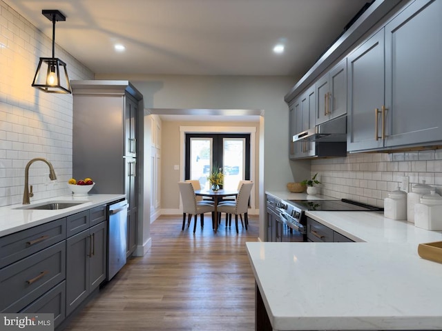 kitchen with gray cabinetry, sink, stainless steel appliances, pendant lighting, and hardwood / wood-style flooring