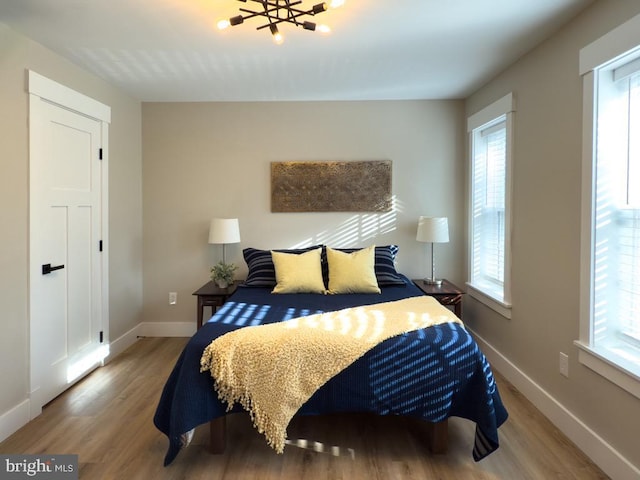 bedroom featuring multiple windows, wood-type flooring, and a notable chandelier