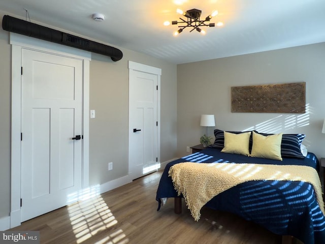 bedroom with hardwood / wood-style floors and a notable chandelier