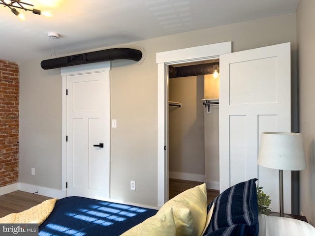 bedroom with a closet, brick wall, and hardwood / wood-style flooring