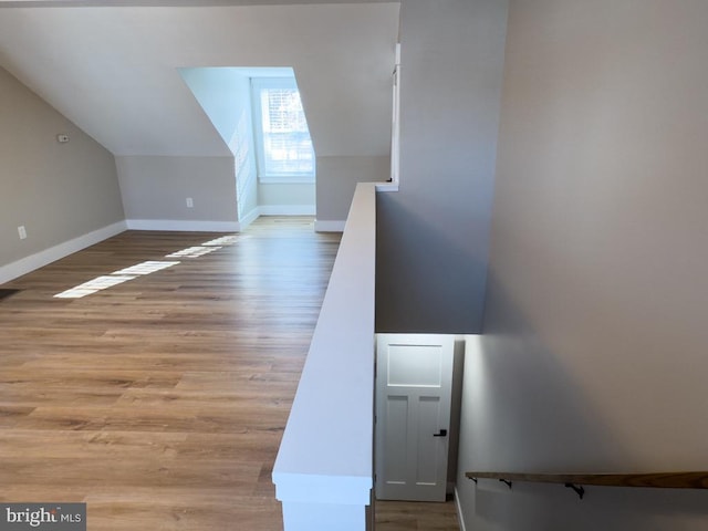 staircase with wood-type flooring and vaulted ceiling