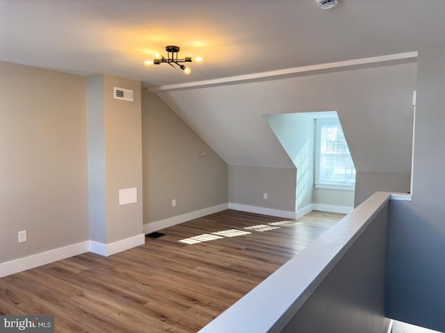 additional living space with hardwood / wood-style floors and vaulted ceiling