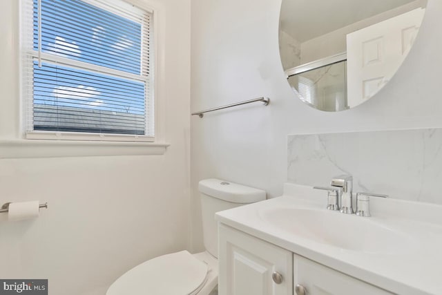 bathroom featuring vanity, toilet, and a shower with door