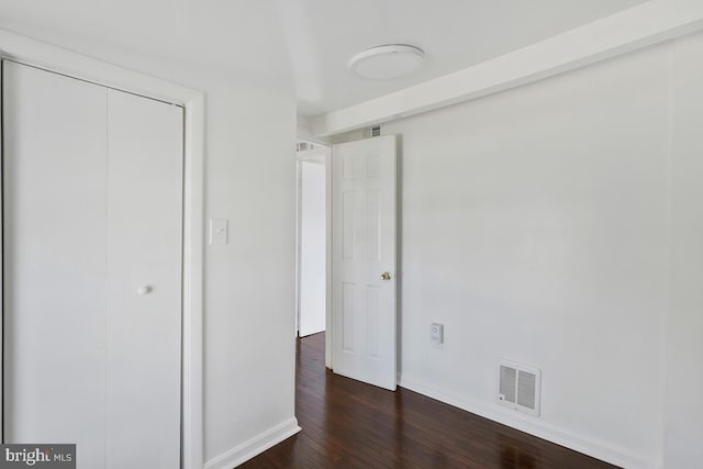 unfurnished bedroom featuring dark wood-type flooring and a closet