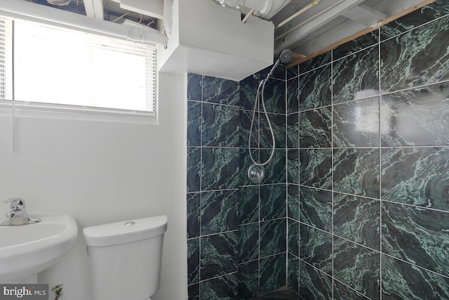 bathroom with sink, toilet, and tiled shower