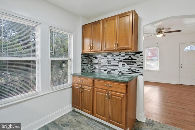 kitchen featuring ceiling fan, decorative backsplash, and light hardwood / wood-style flooring