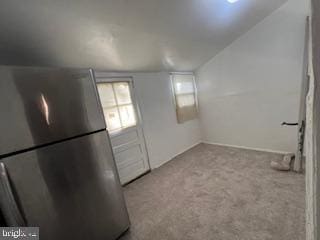 kitchen with stainless steel fridge, light carpet, and vaulted ceiling